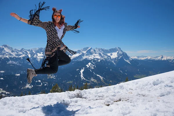 Young woman jumping on top of the mountain in snowy landscape — Stock Photo, Image