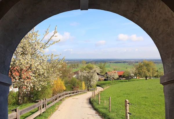 Вид через каменную арку, сельский пейзаж весной — стоковое фото