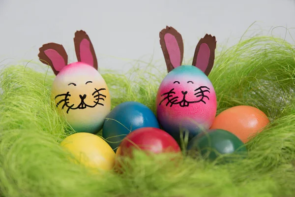 Пасхальное гнездо с разноцветными яйцами и кроликами — стоковое фото