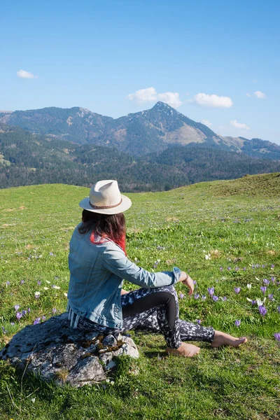 Young woman sitting on a stone in alpine landscape — Stock Photo, Image