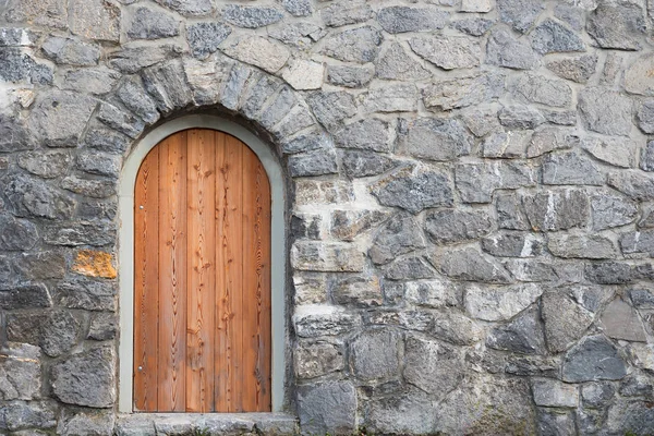 Арочные деревянные двери в природной каменной стене — стоковое фото