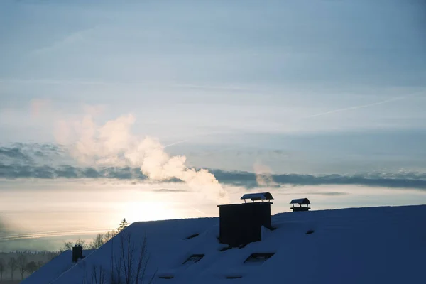 Snöigt hus tak och skorsten med rök, uppvärmningsperiod i winte — Stockfoto