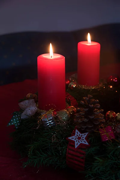 Dwie zapalone czerwone świece na świątecznym wieńcu — Zdjęcie stockowe