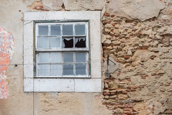 Vieja pared desmenuzada con yeso en escamas y ventana rota, abandonar —  Fotos de Stock