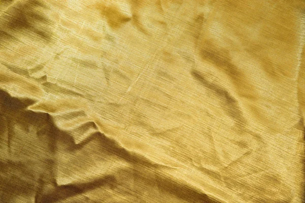 Biraz kırışıklığı olan altın tekstile yakın çekim.