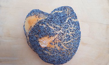 Tahta arka planda mavi haşhaş tohumu olan kalp şeklinde bir çörek.