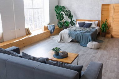 Yatak odası ve yaşam alanı olan modern stüdyo daire tasarımı. Panoramik pencereli otel odası, büyük boy yatak, kanepe ve kahve masası. Şehir konsepti.