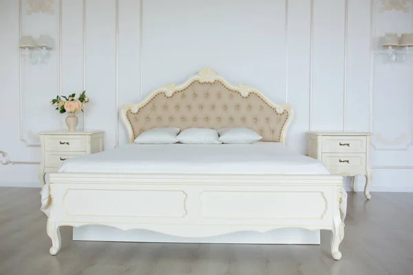Спальня в мягких светлых тонах. большая удобная двуспальная кровать в элегантной классической спальне — стоковое фото