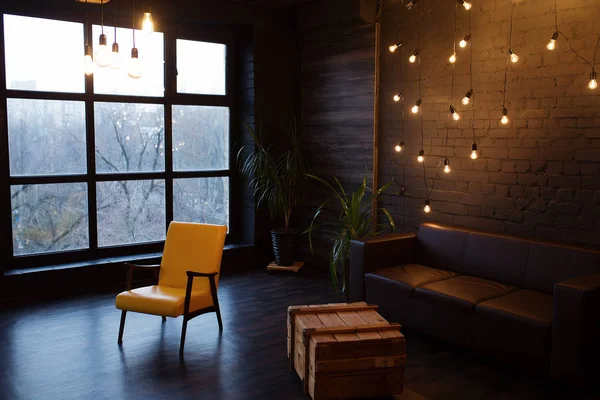 Современный интерьер в темном цвете с кожаным диваном и большим окном. Гостиная в стиле лофт — стоковое фото