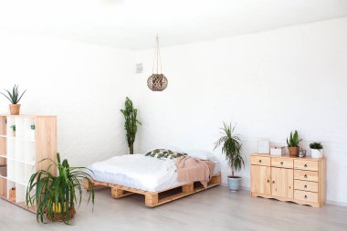 Lüks stüdyo dairesinin rahat yatak odası. Büyük panoramik penceresi ve yeşil bitkisi olan, tavan arası tarzı bedava..