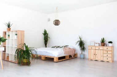 Lüks stüdyo dairesinin rahat yatak odası. Büyük panoramik penceresi ve yeşil bitkisi olan, tavan arası tarzı bedava..