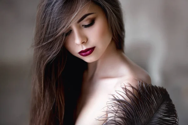 Beautiful young woman. Dramatic indoor portrait of sensual brunette female with long hair. Sad and serious girl.