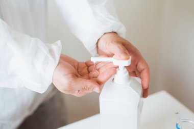 Coronavirus veya COVID-19 önleme kavramı. Doktor ellerini dezenfektan ya da pompa şişesinden alkol jeli kullanarak kapat..