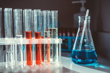 Bir rafta renkli sıvılar olan matara ve test tüpleri.