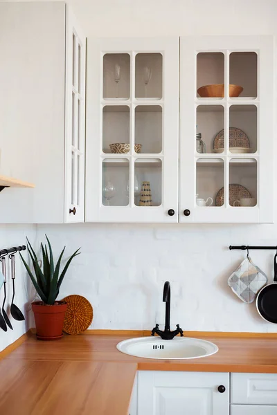 Bílý kuchyňský dřez a černý kohoutek v kuchyni. Interiér kuchyňského pokoje v bytě. Zabudované spotřebiče. Kuchyňský spotřebič. Domácí spotřebiče — Stock fotografie