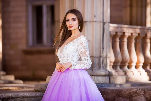 Fashion outdoor photo of beautiful sensual girl with dark hair in elegant dress posing in ancient architecture. — Stock Photo, Image