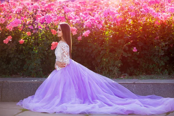 Schöne Mädchen in elegantem Kleid posiert in der Nähe von bunten Blumen. Kunstwerk einer romantischen Frau . — Stockfoto