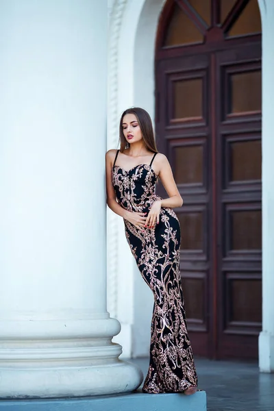 Fashion outdoor foto van mooie sensuele meisje met donker haar in elegante jurk poseren in oude architectuur. — Stockfoto