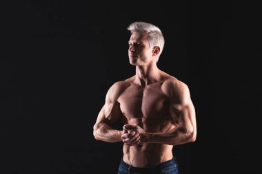 Dramatik ışıktaki yakışıklı atletik adam. Güçlü vücut geliştirici, mükemmel omuzları, pazıları, kol kasları, sırtı, deltası ve göğsü var. Kuvvet ve motivasyon