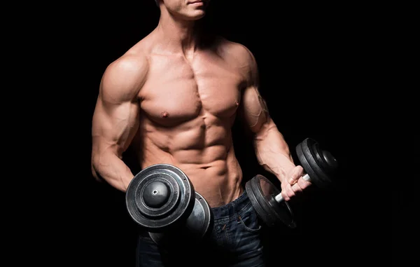 Handsome power athletic man with dumbbell confidently looking forward. Strong bodybuilder with six pack, perfect abs, shoulders, biceps, triceps and chest. Strength and motivation — Stock Photo, Image