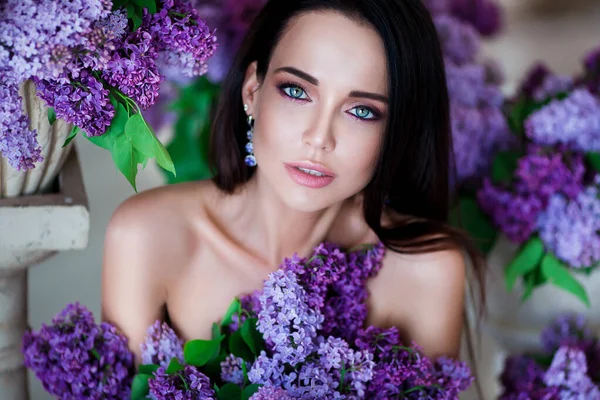美の肖像画。紫色の花の間に座って官能的な唇を持つ美しい女性。化粧品、化粧品。香水だ. — ストック写真