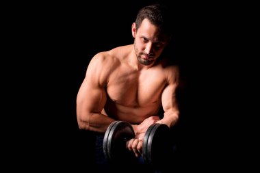 Fitness konsepti. Mükemmel karın kasları, pazıları ve göğsü olan kaslı ve seksi bir adam. Dambıl tutan atletik vücutlu iri yarı bir erkek..