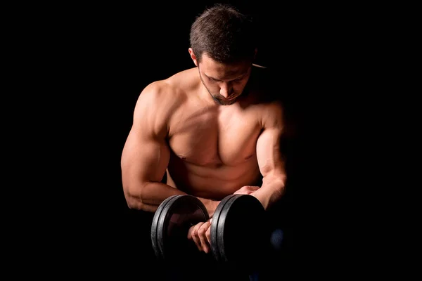 Homme fort avec le corps musclé travaillant. Exercice de poids avec haltère sur fond noir . — Photo