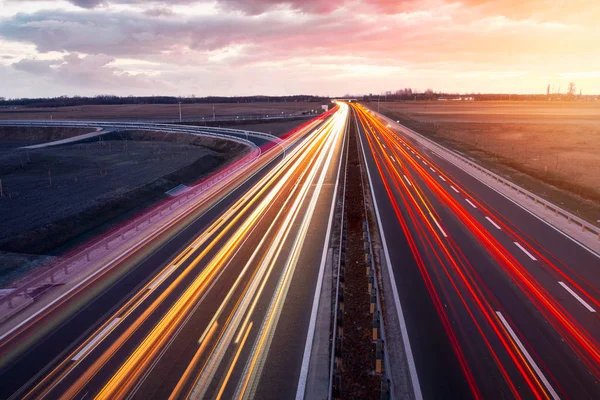 Робоче шосе з швидкісними транспортними засобами на красивому заході сонця — стокове фото