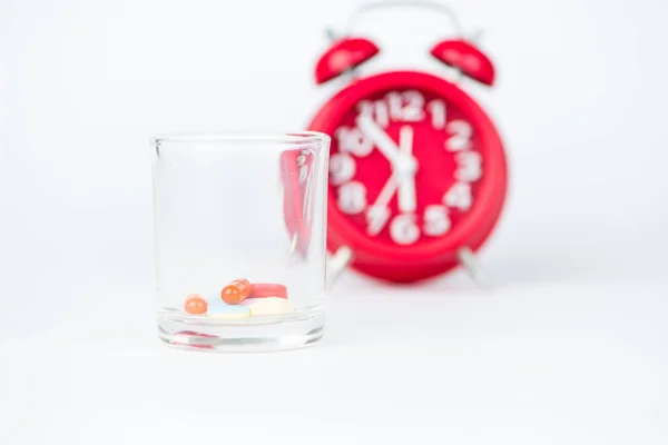 El vidrio dispensador y el reloj rojo muestran el concepto de hora de la medicina — Foto de Stock
