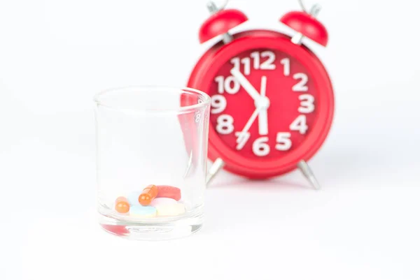 El vidrio dispensador y el reloj rojo muestran el concepto de hora de la medicina — Foto de Stock