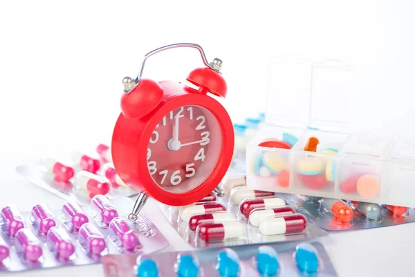 Red alarm clock and medical blister pack — Stock Photo, Image