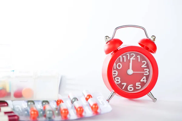 Reloj despertador rojo y blister médico —  Fotos de Stock