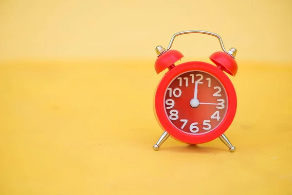 Reloj despertador rojo sobre fondo amarillo — Foto de Stock