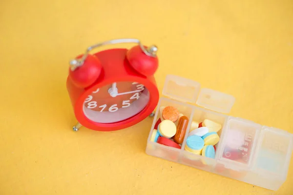 Red alarm clock and daily pill box — Stock Photo, Image