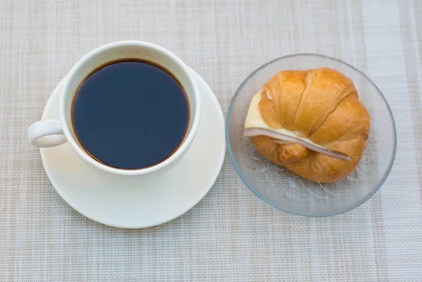 Una taza de café negro con jamón y croissant de queso — Foto de Stock