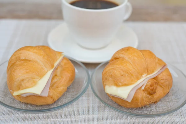 Croissant de presunto e queijo com fundo de café — Fotografia de Stock