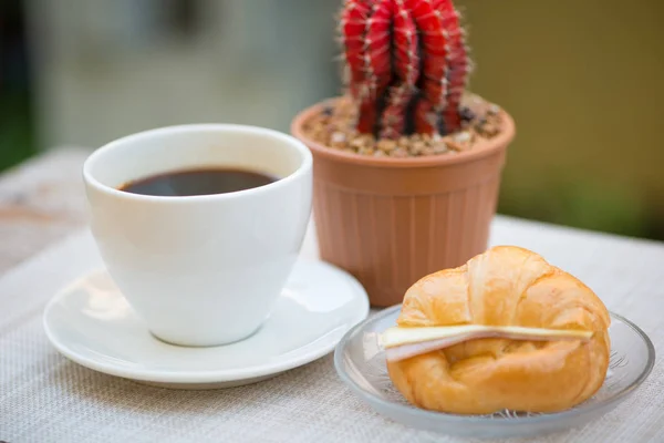 Una taza de café negro con jamón y croissant de queso — Foto de Stock