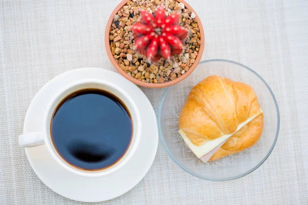 Uma xícara de café preto com presunto e croissant de queijo — Fotografia de Stock