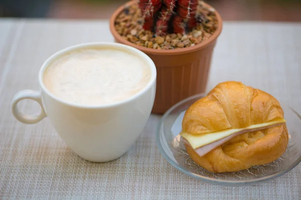 Uma xícara de café com presunto e croissant de queijo — Fotografia de Stock
