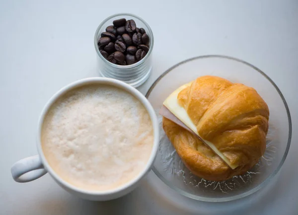 Uma xícara de café com presunto e croissant de queijo — Fotografia de Stock