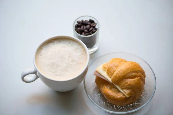 Uma xícara de café com presunto e croissant de queijo — Fotografia de Stock