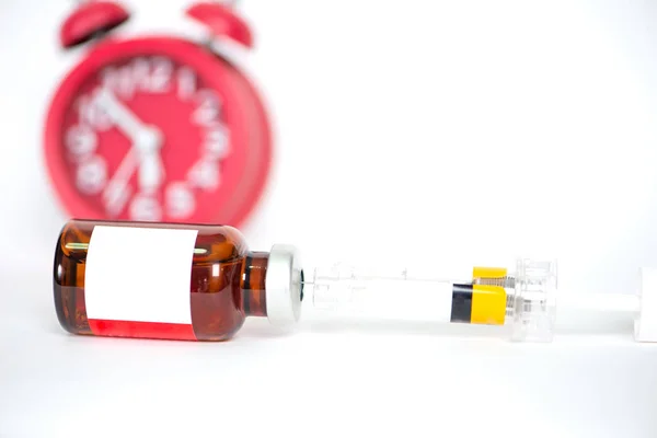 Injection vials and syringe on redclock background show medicine — Stock Photo, Image