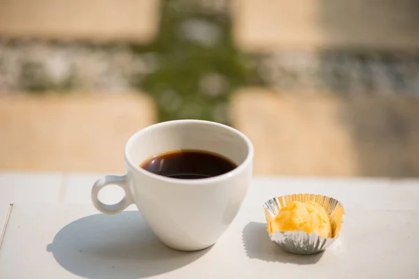 A white cup and black coffee with bakery