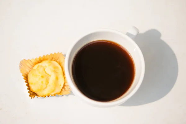 A white cup and black coffee with bakery