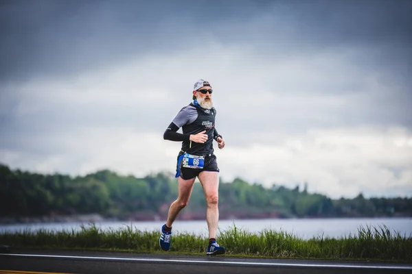 Maratonista sênior no lado da estrada e do oceano — Fotografia de Stock