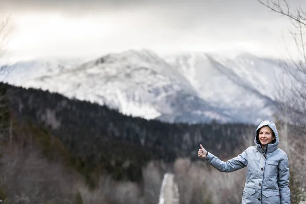 山に冬道でヒッチハイクする女性 — ストック写真