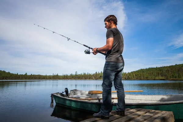 Hombre Pesca trucha desde una cubierta en un lago — Foto de Stock