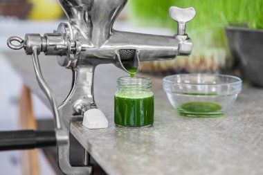 Mutfak tezgahından bir Juicer kullanarak eylem içinde buğday çimi