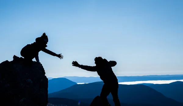 Casal em silhuetas ajudando uns aos outros para o sucesso — Fotografia de Stock