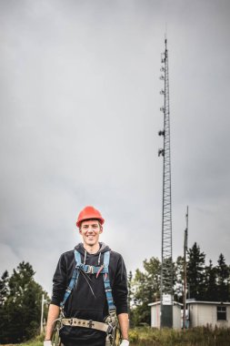 Koşum takımı ayakta telekomünikasyon Tower'da ile Üniformalı erkeklere neşeli teknisyen